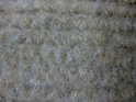 Close-up van de beige stof van een trapmat met dikke, zachte vezels.