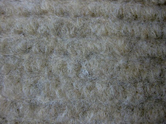 Close-up van de beige stof van een trapmat met dikke, zachte vezels.