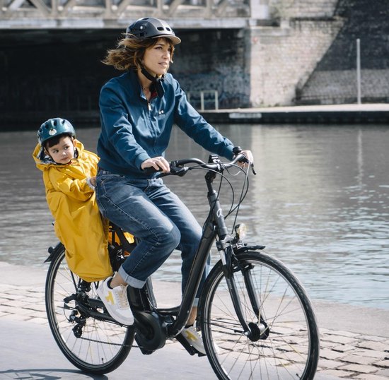 Vrouw op elektrische fiets met kind in geel regenponcho in fietsstoeltje.