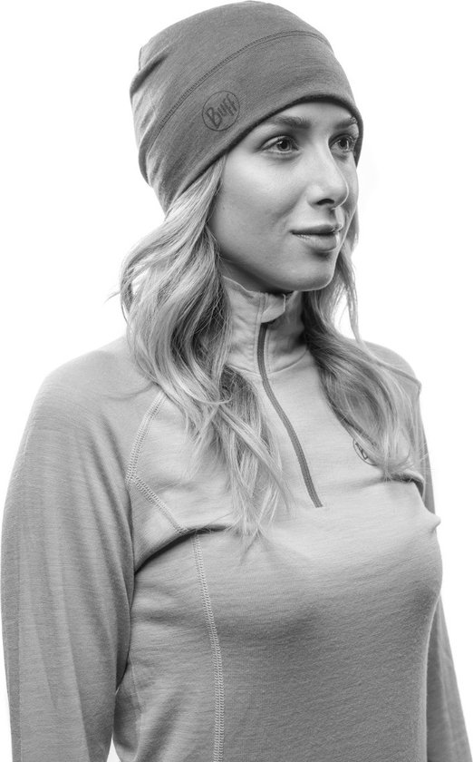 Vrouw met golvend haar, draagt effen muts en effen top met halve rits en Buff-logo.