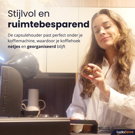 Femme en chemise blanche tenant une capsule Dolce Gusto, avec une machine à café et un support tiroir.