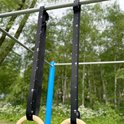 Zwarte ophangbanden met witte maatstreepjes voor gymringen, bevestigd aan een rek.