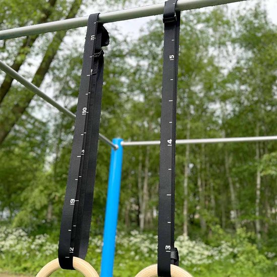 Zwarte ophangbanden met witte maatstreepjes voor gymringen, bevestigd aan een rek.