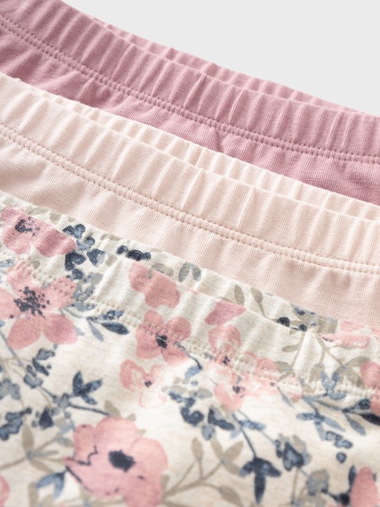 Drie broekjes met bloemenprint en effen kleuren, close-up van de elastische tailleband.