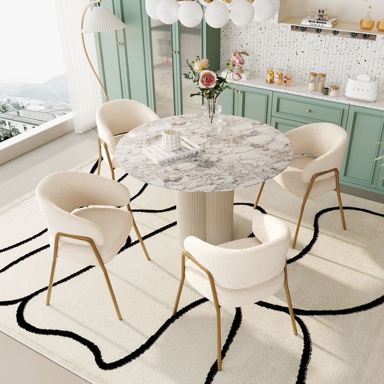 Quatre chaises de salle à manger en teddy crème sur pieds dorés, table ronde en marbre avec vase de fleurs.