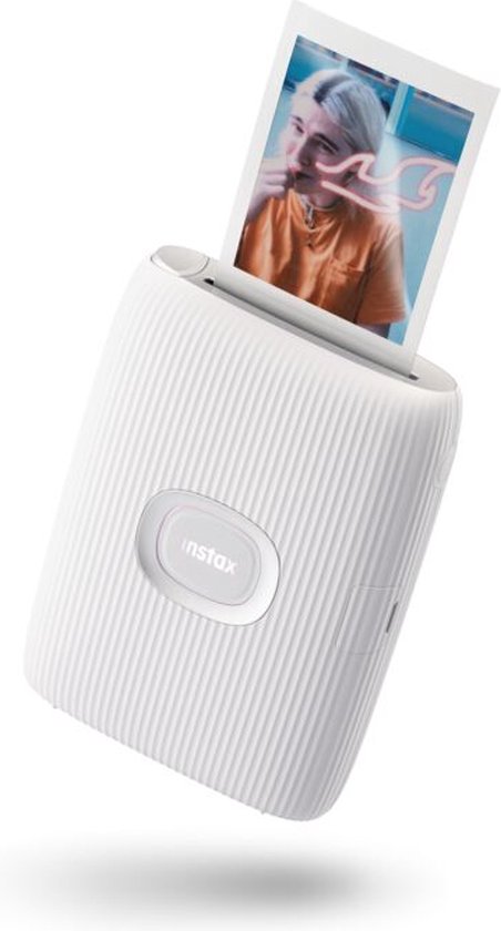Witte Instax Mini Link 2 printer met een Instax foto eruit printend, met op de foto een persoon die naar de camera lacht.