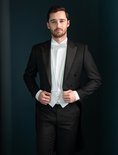 Man met wit vest, witte vlinderdas en wit overhemd onder een zwart rokkostuum.