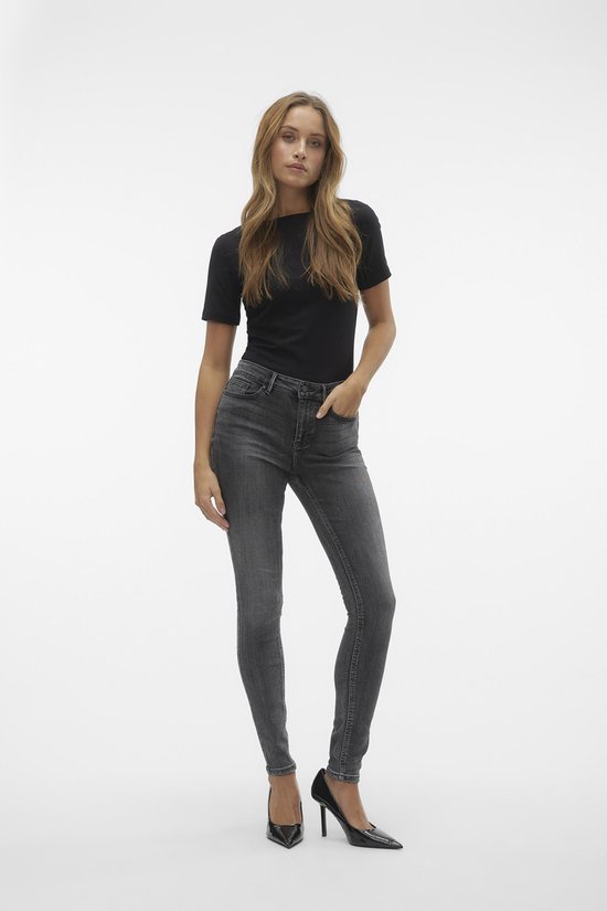Model in strakke grijze jeans met hoge taille en zwart T-shirt.