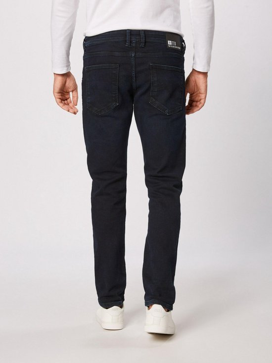 Een man draagt een donkerblauwe slim fit jeans, van achteren gezien.