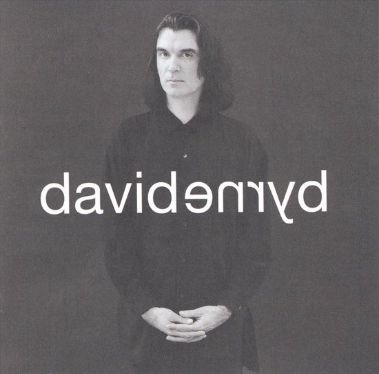 Een man met lang, donker haar draagt een zwart overhemd. "davidənyd" staat in witte letters over de borst.