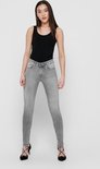 Model in zwarte tanktop en grijze skinny jeans, met hoge hakken.