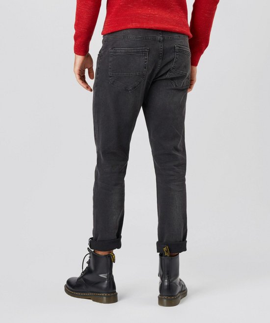 Model draagt donkergrijze jeans met regular fit en omgeslagen broekspijpen, met zwarte laarzen.