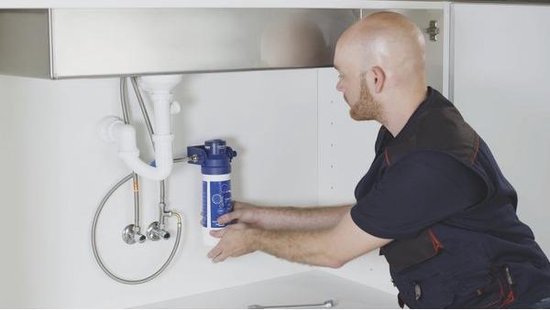 Man installeert een witte en blauwe boiler onder een gootsteen.