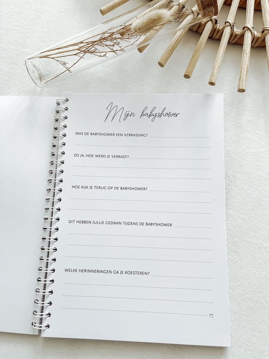 Wit invulboek met de titel 'Mijn babyshower' en gedroogde bloemen.