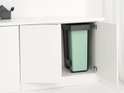 Mintgroene Brabantia prullenbak in een zwart frame, ingeschoven in een keukenkastje.