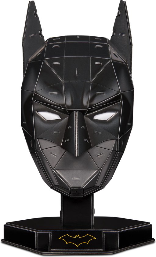 Zwart, geometrisch Batman-masker met witte ogen, staand op een zwarte standaard met goudkleurig Batman-logo.