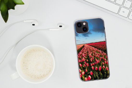 iPhone 13 hoesje met een weids veld met roze en rode tulpen, op een bureau naast een kopje koffie en oordopjes.
