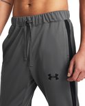 Grijze trainingsbroek met trekkoord, zwarte streep op de zijkant en een zwart Under Armour logo.