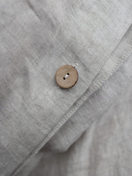 Beige linnen dekbedovertrek met een ronde houten knoopsluiting.