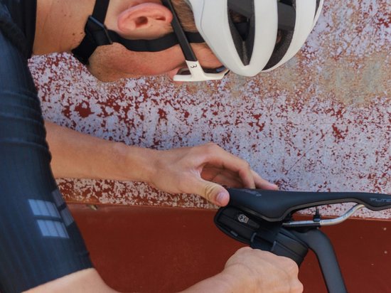 Een man stelt een zadeltas in onder een fietszadel.