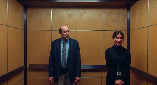 Man en vrouw staan in een lift met houten wanden.