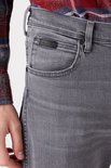 Detail van de voorzak van een donkergrijze straight-fit jeans met een zwarte Wrangler-logopatch.