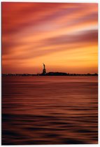 WallClassics - Dibond - Vrijheidsbeeld in New York van Ver met Zonsondergang - 70x105 cm Foto op Aluminium (Wanddecoratie van metaal)