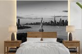 Behang - Fotobehang Vrijheidsbeeld en skyline van New York -zwart-wit - Breedte 220 cm x hoogte 220 cm