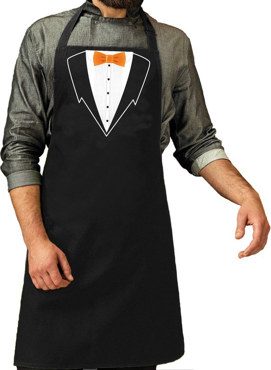 Tablier noir avec un smoking imprimé et un nœud papillon orange. Porté par un homme.