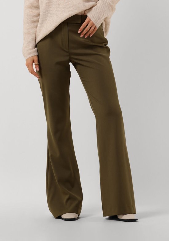 Model draagt een beige trui en een donkergroene pantalon met wijde pijpen.
