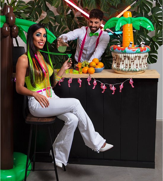 Vrouw in neon-outfit met cocktailketting bij bar, man serveert drankjes bij een tropisch themafeest.