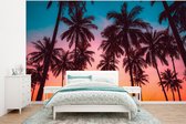 Behang - Fotobehang Palmboom - Zonsondergang - Horizon - Strand - Oranje - Roze - Breedte 320 cm x hoogte 240 cm