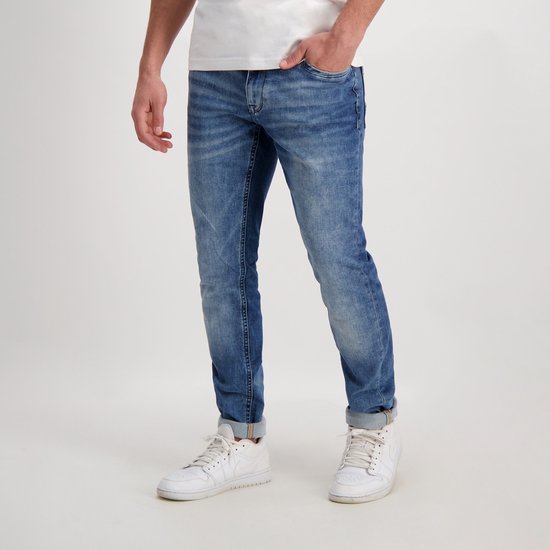 Blauwe denim jeans met lichte wassing, gedragen door een man met witte sneakers.