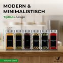 Zes glazen kruidenpotjes met zwarte etiketten en zilveren deksels, gevuld met kurkuma, oregano, anijs, kardemompeulen, laurierblad en paprikapoeder.