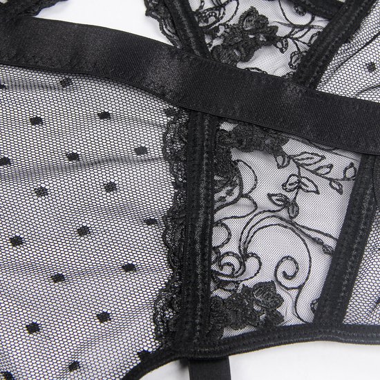 Detail van zwart kant met polkadots en geborduurde bloemen.