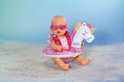 Zittende baby pop met hartjes zonnebril, glitter zwemband met eenhoorn en een glitter zwempak.