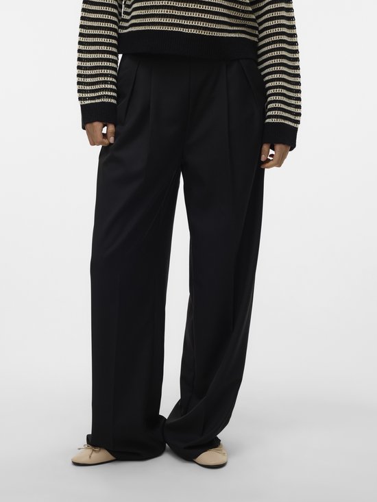 Vrouw draagt een zwarte wijde broek met plooien aan de voorkant en een gestreepte trui.