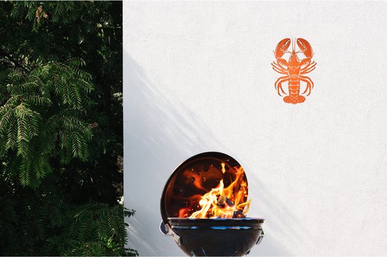 Oranje kreeft-decoratie aan een witte muur, met een barbecue met vlammen op de voorgrond.