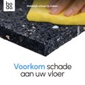 Een hand met een gele spons maakt een zwarte, dikke anti-trillingsmat schoon.