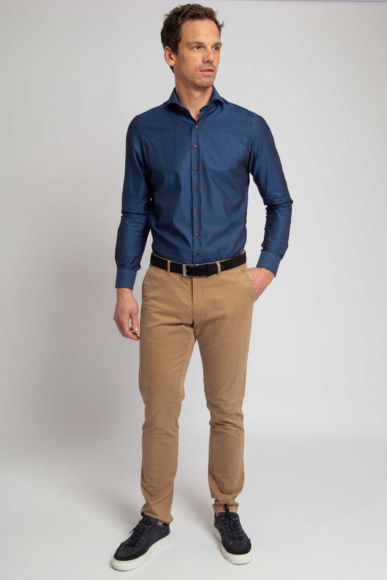 Man met donkerblauwe blouse, zwarte riem en lichtbruine chino broek.