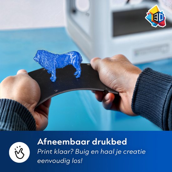 Blauwe leeuw op een zwart, flexibel drukbed dat door handen wordt vastgehouden. Achtergrond is een blauwe 3D-printer. Tekst: 'Afneembaar drukbed'.