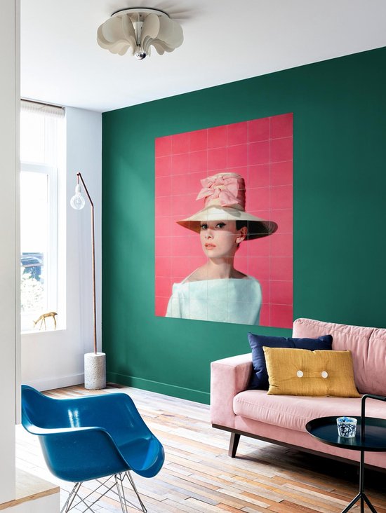 Audrey Hepburn portant un grand chapeau de paille et un nœud rose sur fond rose.