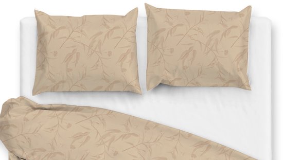 Twee beige kussenslopen met een subtiel bladermotief op een opgemaakt bed.
