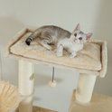 Een jonge kat met zilveren en witte vacht ligt op een beige platform van een krabpaal.