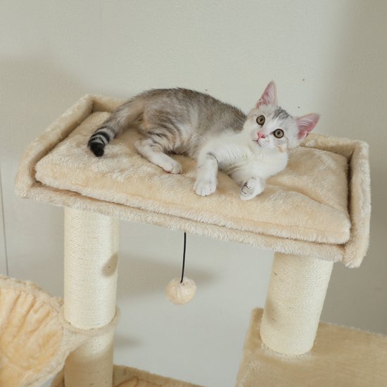 Een jonge kat met zilveren en witte vacht ligt op een beige platform van een krabpaal.