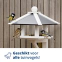 Drie vogels (twee pimpelmezen en een huismus) op een witte houten voederhuis met een grijze dak.