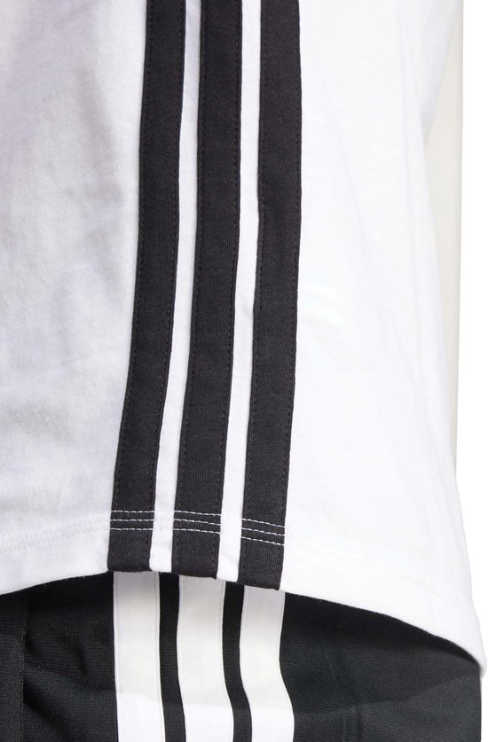 Detail van een wit T-shirt met zwarte Adidas strepen.