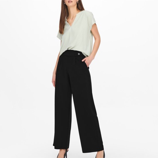 Model met zwarte wijde pantalon met hoge taille, sierknoop en steekzak.