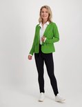 Model draagt een felgroene blazer over een witte blouse, met een zwarte broek en witte sneakers.