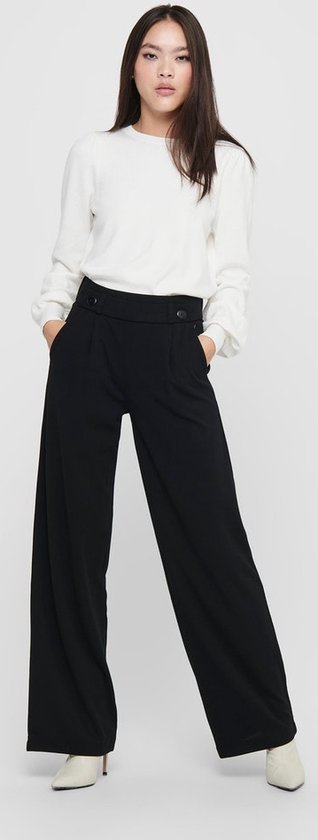 Model met zwarte wijde broek, met knoopdetail, gedragen met witte top.